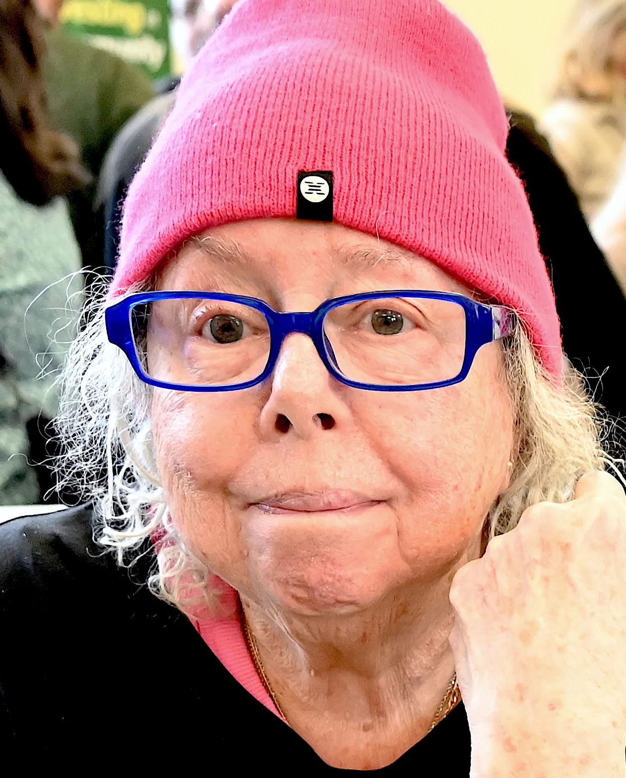 Joyce Marcel wearing a bright pink knit hat and blue glasses